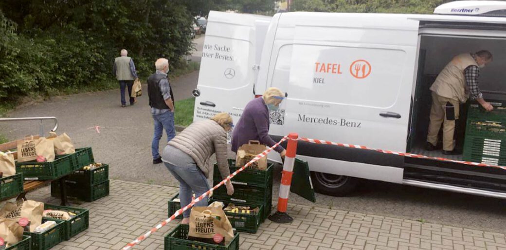 Menschen mit gepackten Lebensmitteltüten vor einem Transporter